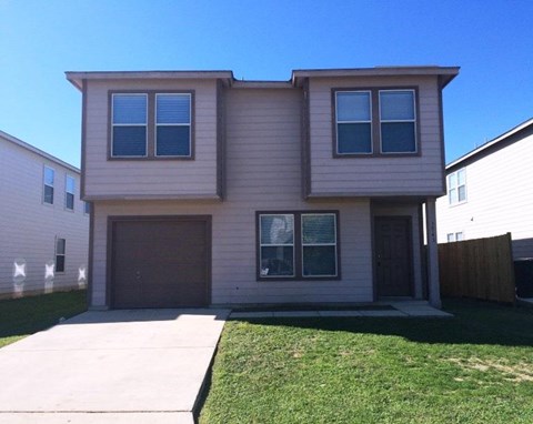 a tan house with a sidewalk in front of it