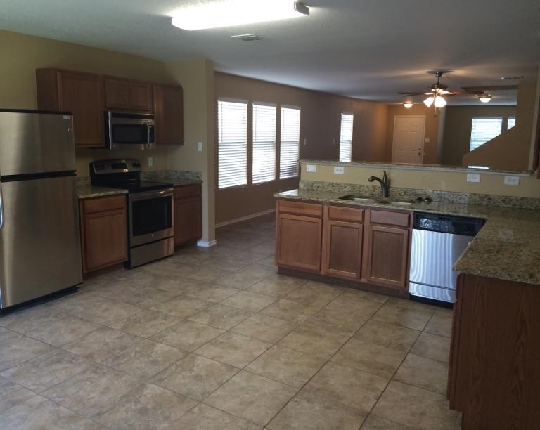 a large kitchen with a sink and a refrigerator