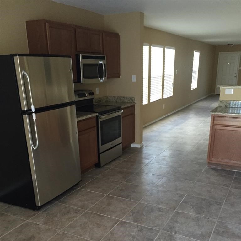 an empty kitchen with a stainless steel refrigerator