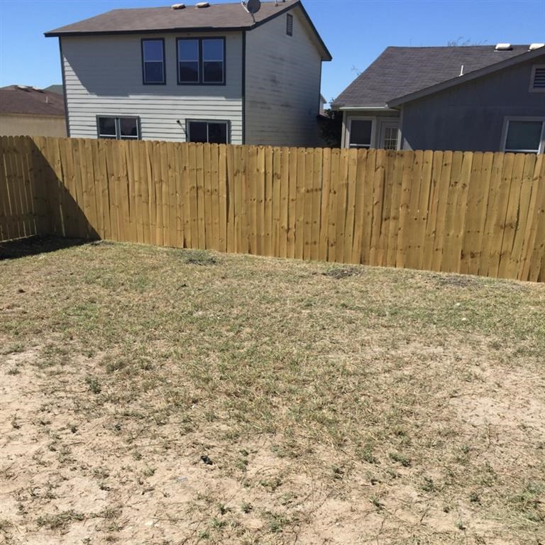 a backyard with a wooden fence and a house behind it