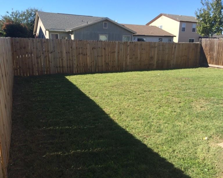 a backyard with a wooden fence and a house