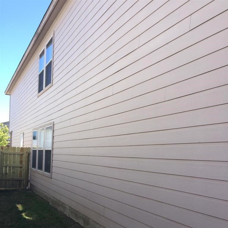 the side of a white house with a wooden fence
