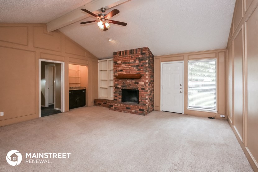 an empty living room with a fireplace and a ceiling fan