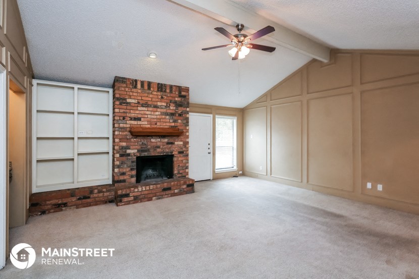 a living room with a brick fireplace and a ceiling fan