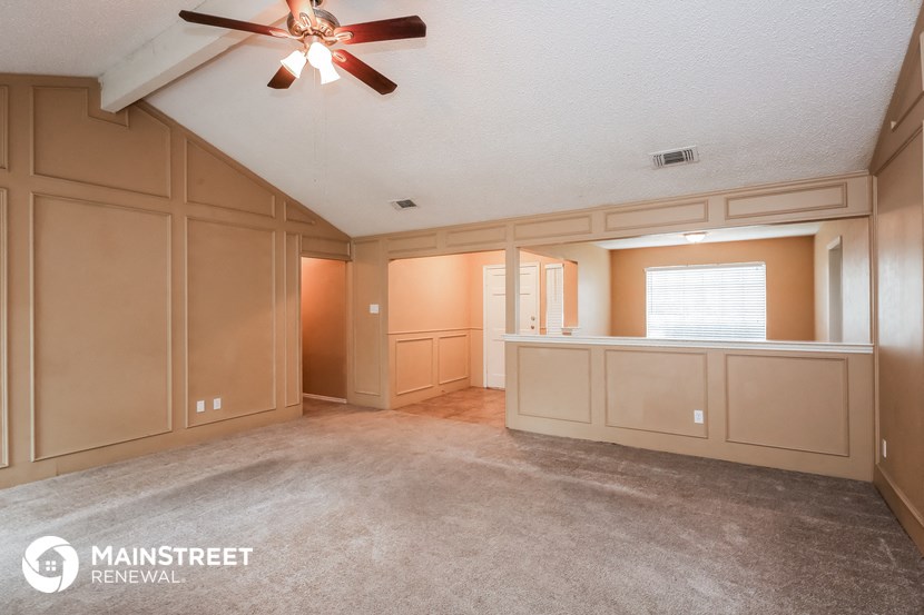the living room and dining room of a house with a ceiling fan