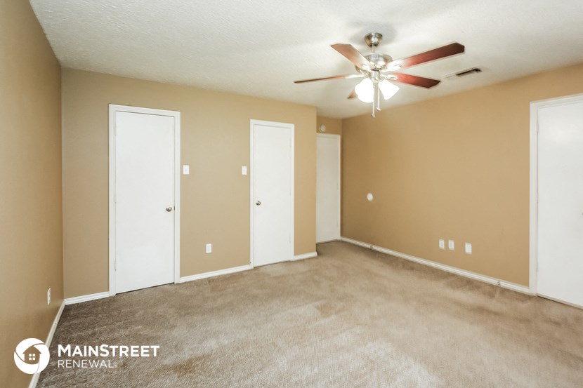 an empty living room with a ceiling fan and doors