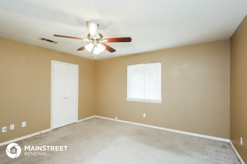 an empty living room with a ceiling fan and a window