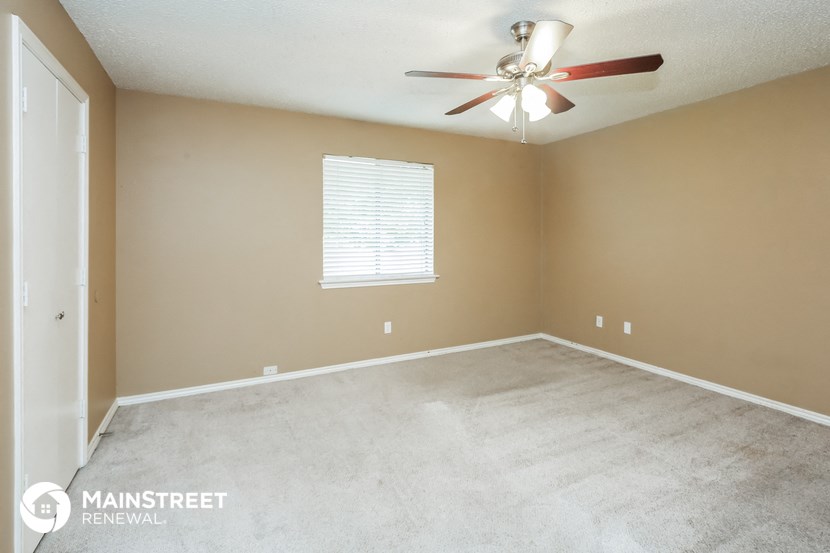 an empty room with a ceiling fan and a window