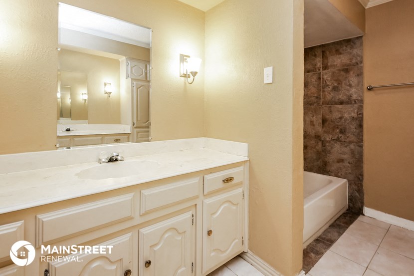 the master bathroom has a large vanity and a tub