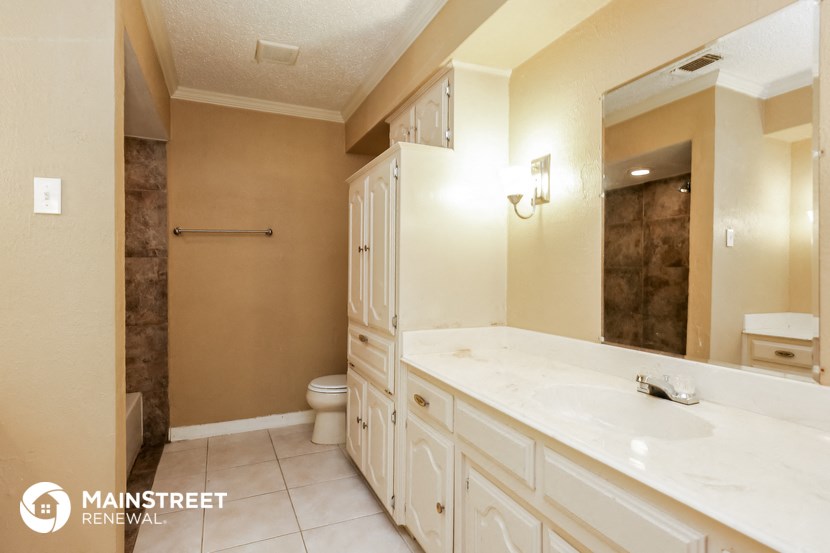 the master bathroom has a large vanity with a large mirror and a toilet