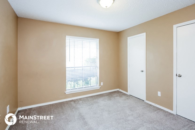 the spacious living room with a large window and carpeted flooring