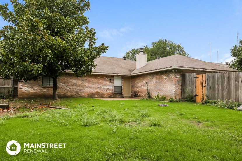 a brick house with a yard and a wooden fence