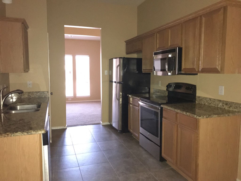 an empty kitchen with wooden cabinets and stainless steel appliances