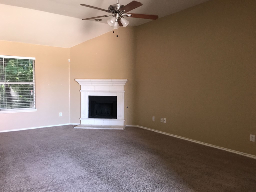 a living room with a fireplace and a ceiling fan