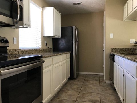 a kitchen with white cabinets and a black refrigerator