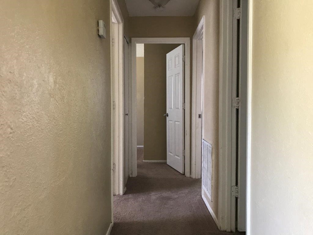 a hallway with a white door and a carpeted floor