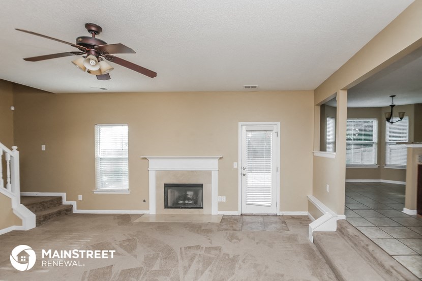 a living room with a fireplace and a ceiling fan