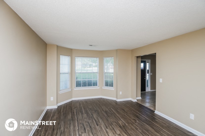 the spacious living room with large windows and wood flooring