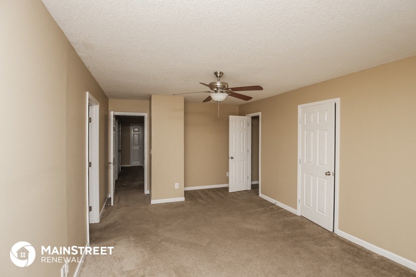 a living room with beige walls and a ceiling fan