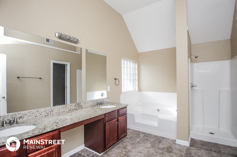 a bathroom with two sinks and a tub and a large mirror