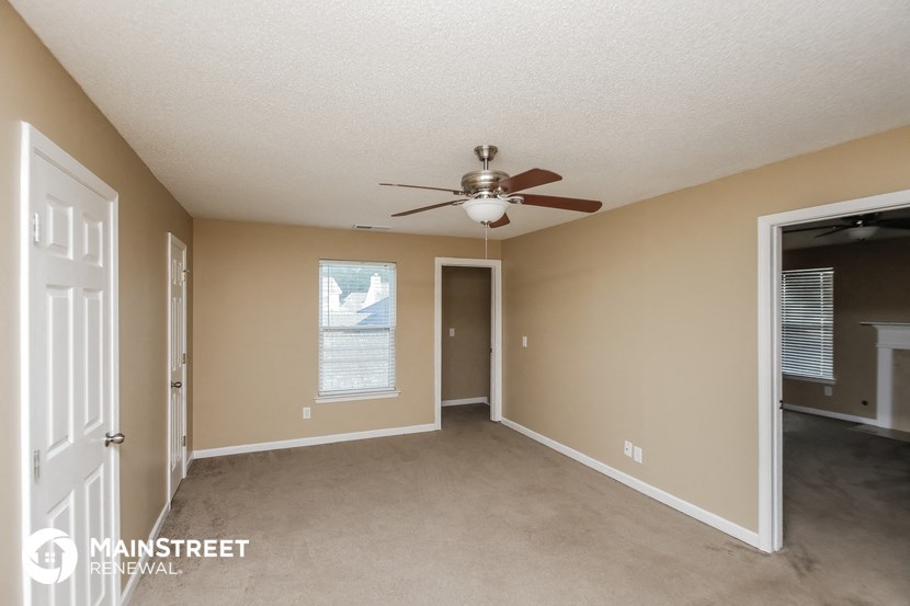 an empty living room with a ceiling fan and a door to a closet