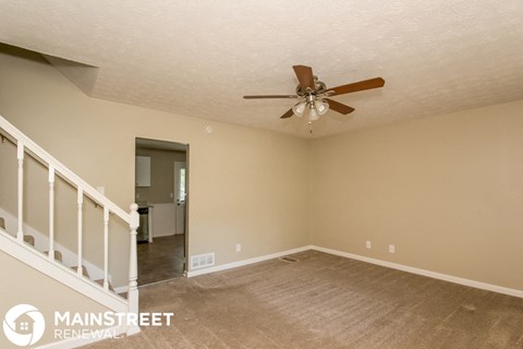 an empty living room with a ceiling fan and a carpet
