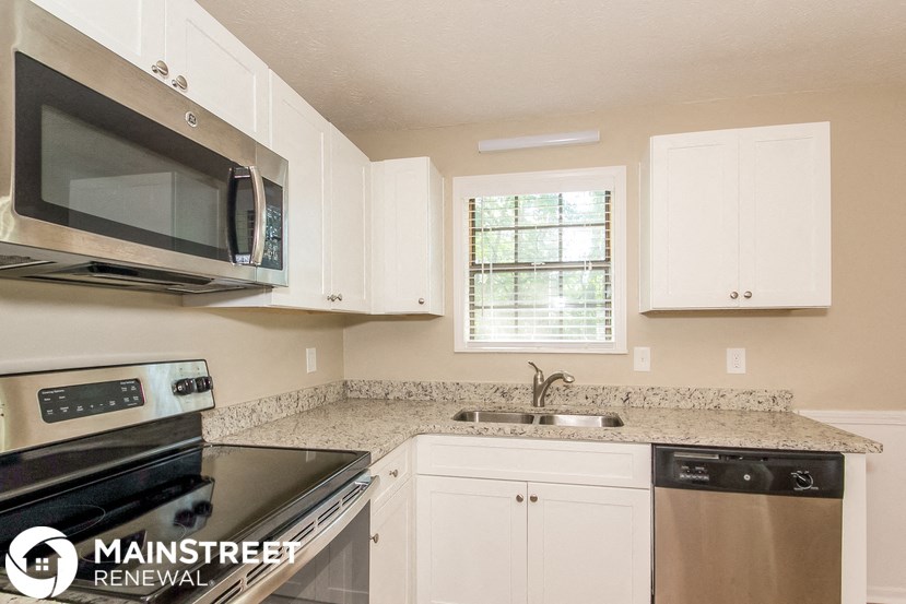 a kitchen with white cabinets and black appliances and granite counter tops