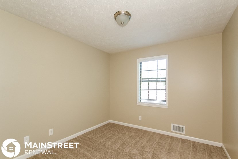 the spacious living room with carpeting and a window