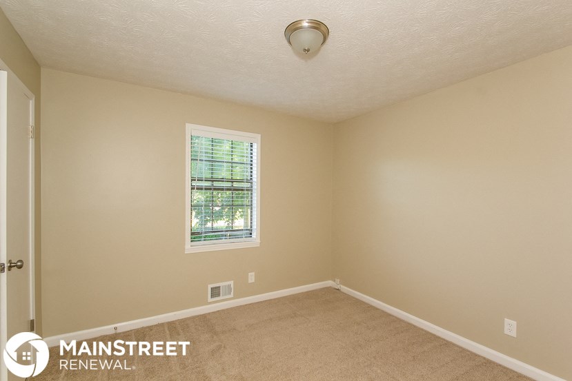 the upstairs bedroom has a carpeted floor and a window