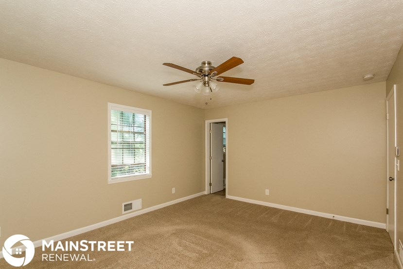 the master bedroom has a ceiling fan and a carpeted floor