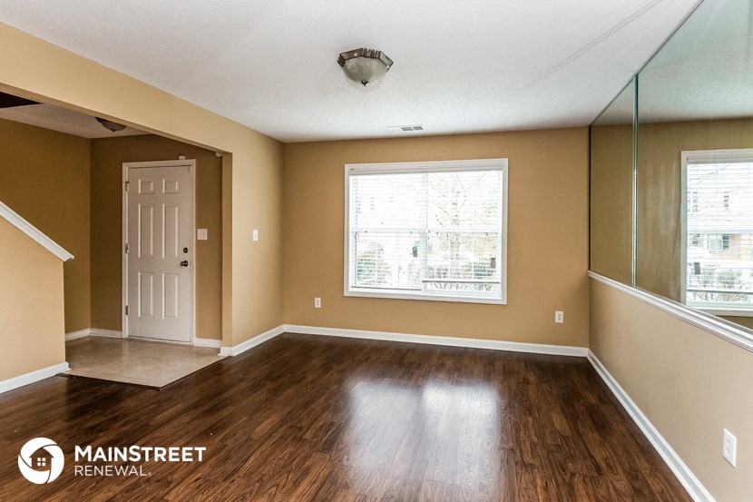 the living room of a home with wood floors and a white door