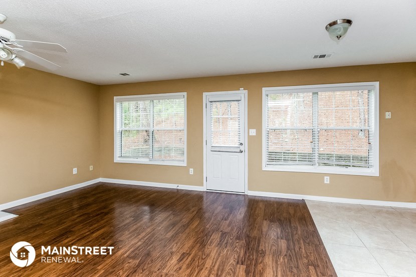 the living room of a home with wood floors and a white door