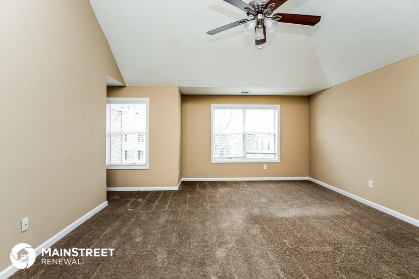 an empty living room with carpet and a ceiling fan