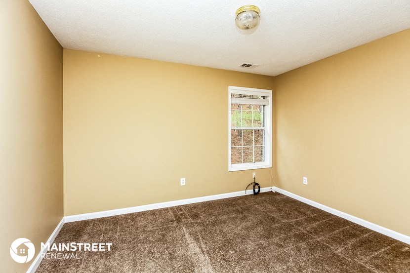 the living room of this home has carpet and a window