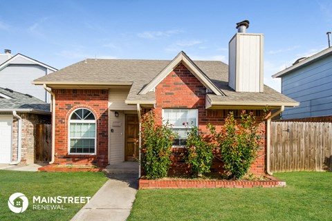 a small brick house with a yard and a sidewalk