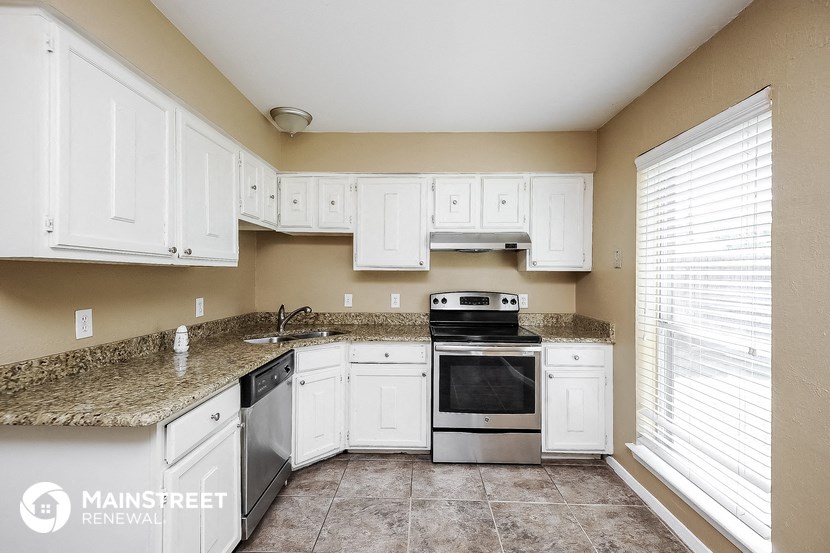 a kitchen with white cabinets and granite counter tops and white appliances