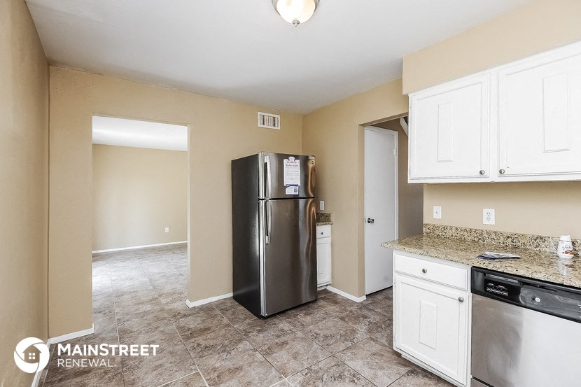 a kitchen with white cabinets and a stainless steel refrigerator