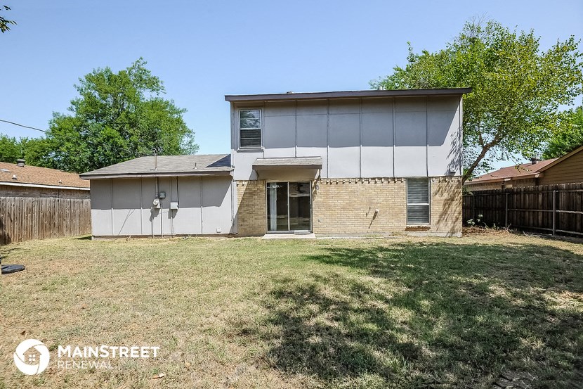 a white and brick house with a yard and a fence