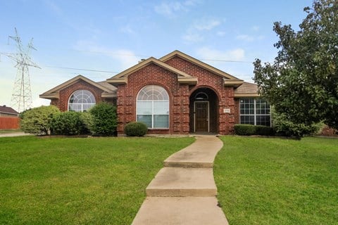 a brick house with a sidewalk in front of it