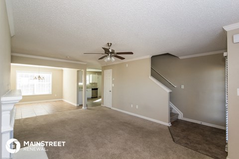 a living room with carpet and a ceiling fan