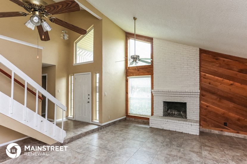 an empty living room with a fireplace and a ceiling fan