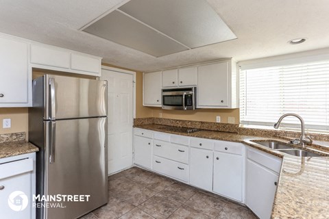 a kitchen with white cabinets and a stainless steel refrigerator