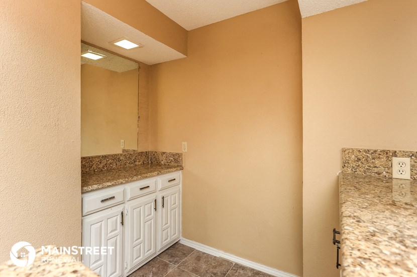 a bathroom with white cabinets and granite counter tops