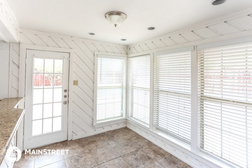 a sun room with white walls and windows and a door