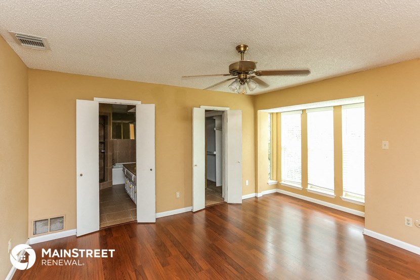 an empty living room with wood floors and a ceiling fan