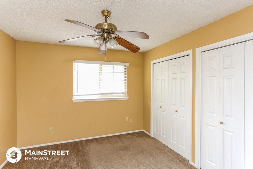 the bedroom of a home with a ceiling fan and two closets
