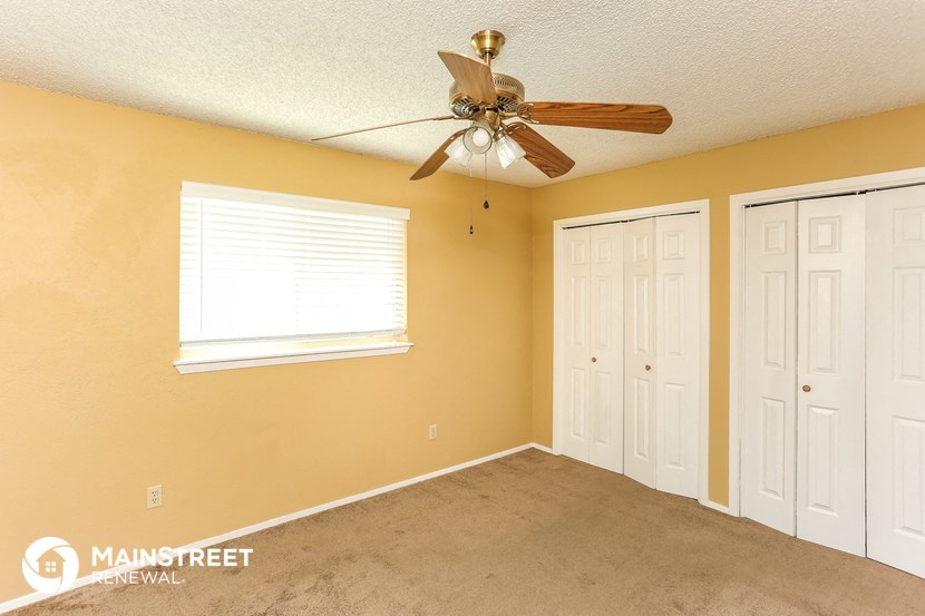 a living room with a ceiling fan and two closets