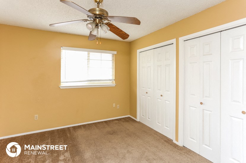 a bedroom with a ceiling fan and two closets
