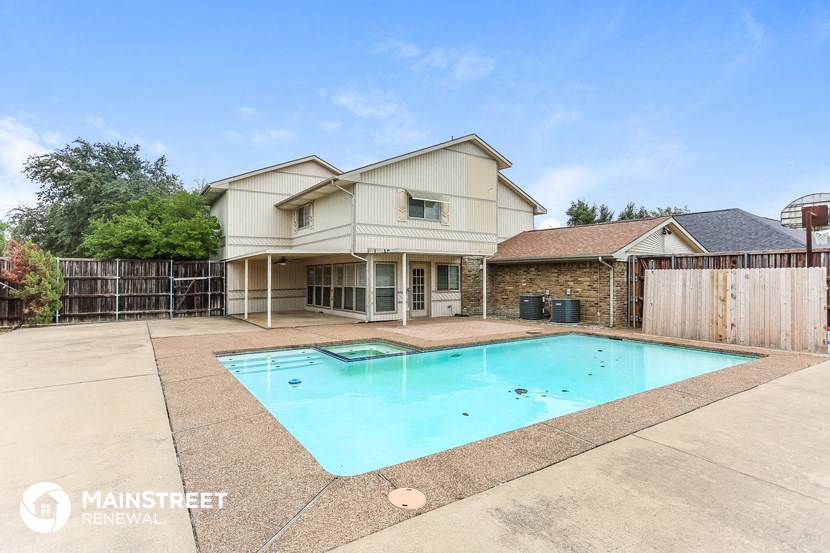 a pool is in the backyard of a house with a fence and a yard