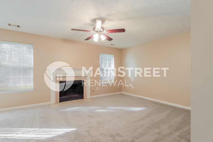 a living room with a fireplace and a ceiling fan